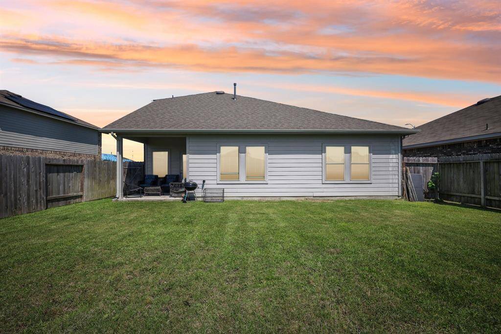 Charming backyard with a covered patio, perfect for relaxing and entertaining under stunning sunset skies.