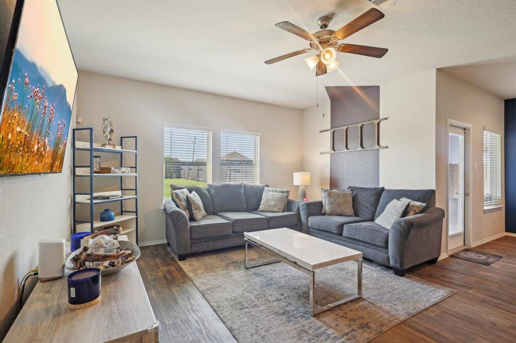 Spacious and inviting living room featuring abundant natural light, elegant hardwood floors, and modern ceiling fan. Perfect for relaxation and entertaining.