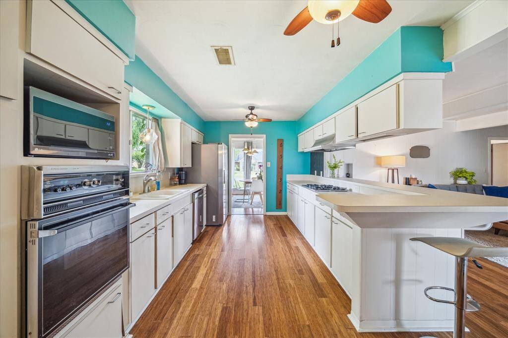 Large bright galley style kitchen with original cabinetry.  The flooring continues throughout the space maintaining a uniform look.