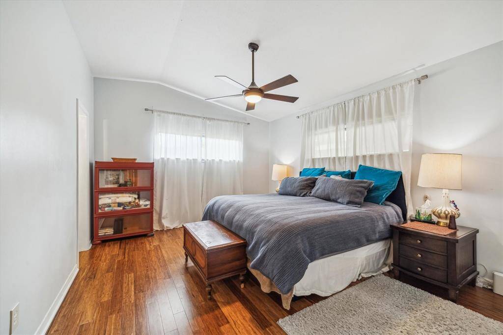 The spacious primary bedroom features a modernist ceiling fan, beautiful flooring, vaulted ceiling, and lots of windows.