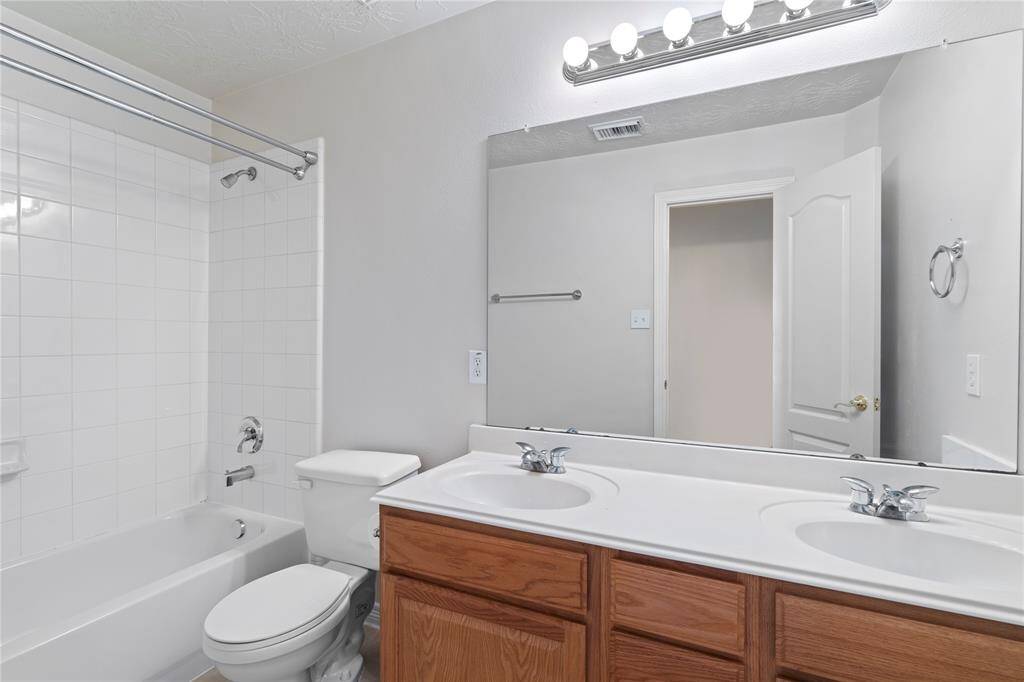 The upstairs secondary bathroom features a dual sink vanity, ample storage, and a clean bright design, perfect for busy mornings or shared use.