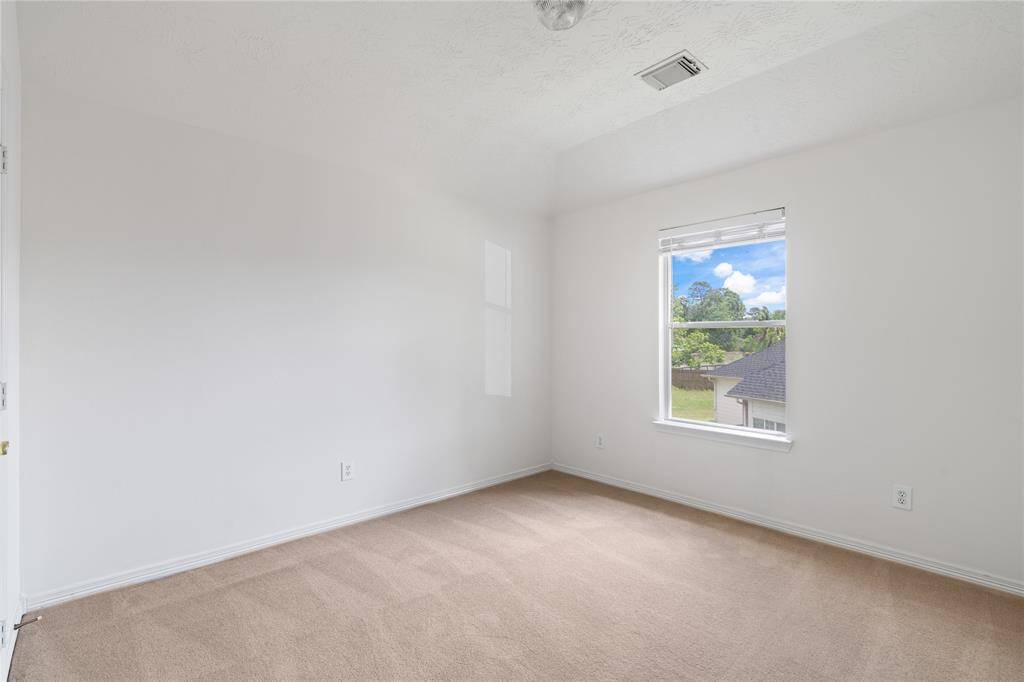 A cozy retreat, this fourth bedroom offers soft lighting, and a spacious layout with plush carpeting designed for comfort.