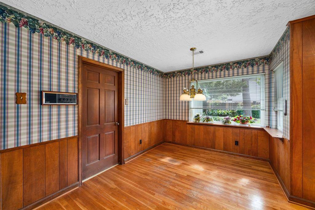 Breakfast room with wood floors has picture windows overlooking back yard. Door in view is to laundry room and powder bath and back door