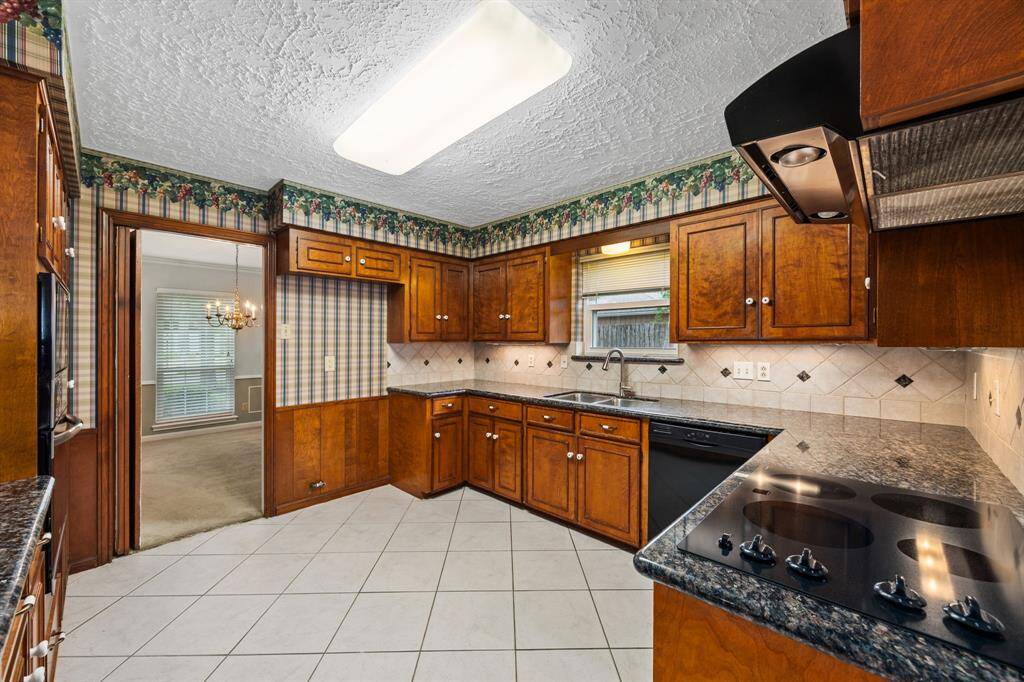 Kitchen showing electric cooktop in granite counters, view into dining room