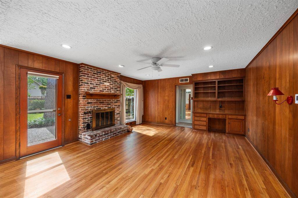 Large family room features wood floors, center brick WBFP, recessed lights.
