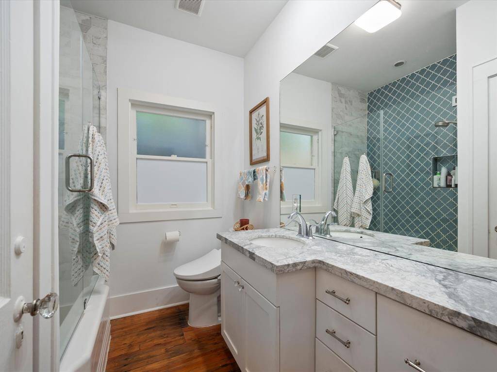 Updated primary bath with beautiful quartz countertops and glass enclosed tub/shower.