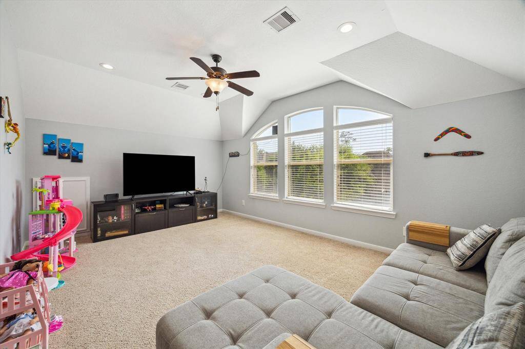 This spacious game room features a vaulted ceiling, large windows for natural light, and neutral carpeting. Perfect for an upstairs family room or playroom.
