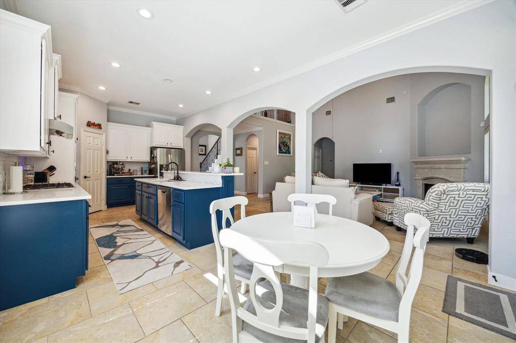 Spacious open-concept kitchen and living area featuring modern blue and white cabinetry, a central island, and a cozy fireplace. The dining area is seamlessly integrated, offering a welcoming space for entertaining.