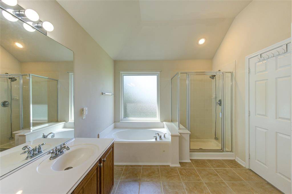 The en suite primary bath features dual sinks, a relaxing soaking tub, and a separate walk-in shower, offering both comfort and functionality.
