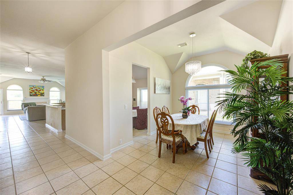 The formal dining room impresses with a vaulted ceiling, an oversized window that floods the space with natural light, and a gorgeous chandelier that adds a touch of sophistication.