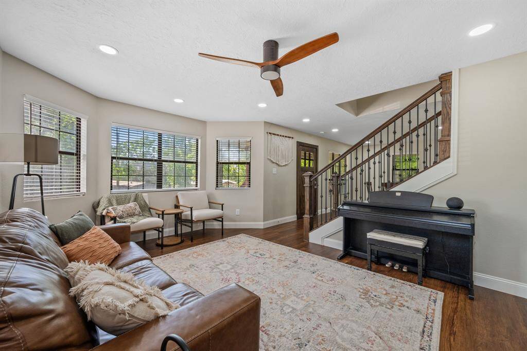 On the other side of the gorgeous, wrought iron and wooden staircase is the living room. This well-lit and warm living area offers plenty of room, and ample natural light from its large windows.