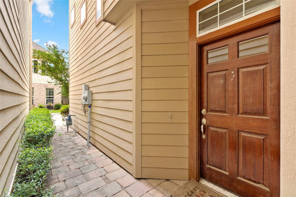 Private front entry with a charming walkway lined by lush greenery and pavers. Tucked between neighboring homes, this low-maintenance entrance offers added privacy and a quiet welcome into the home.