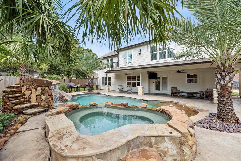 Sizeable rocks trim the rounded edges of the sparkling swimming pool. Reminiscent of the Bahamas, bright green palm leaves drape over the poolside for an added tropical effect.