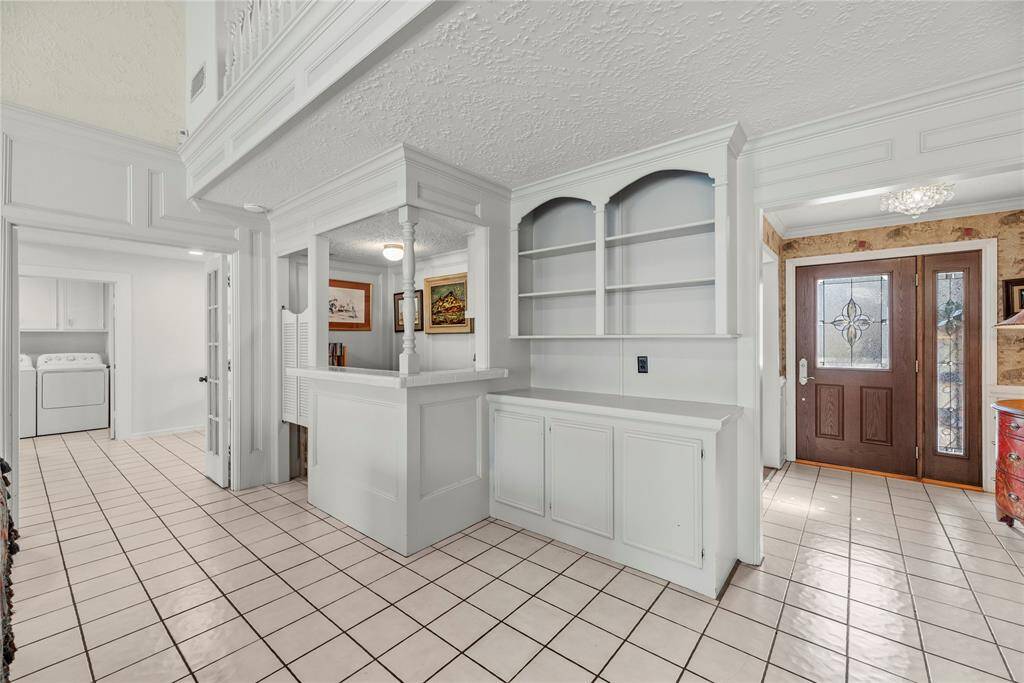Bright entryway with tiled flooring.  The family room features a wet bar and built-in shelving area near the entryway.