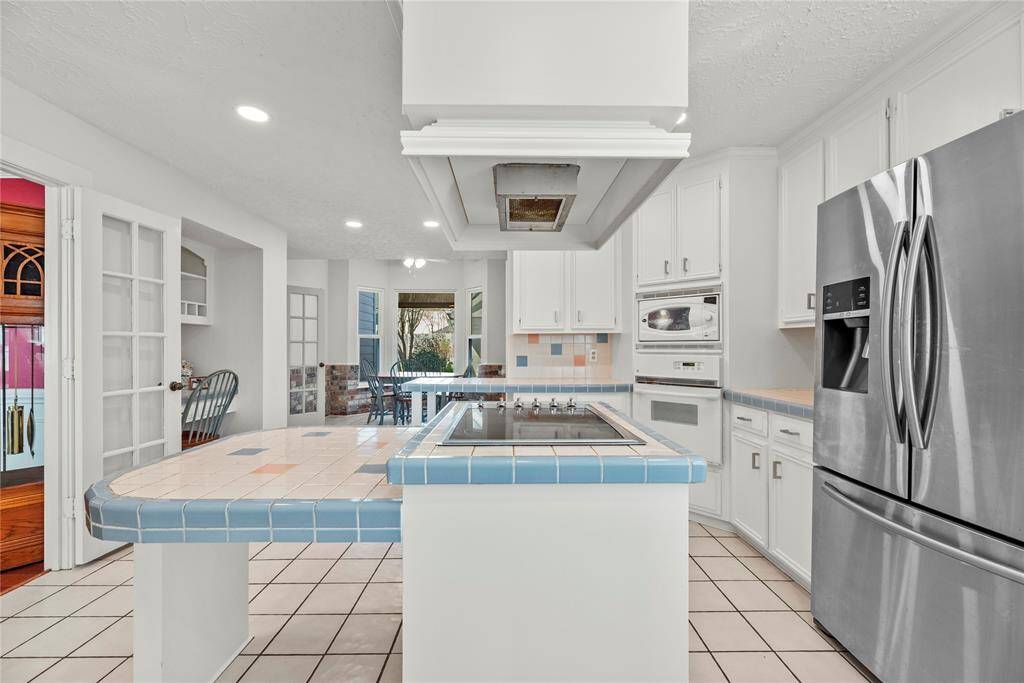 The homes kitchen features a functional layout with a central island cooktop.  These original solid wood cabinets have been painted.  The tile countertops and backsplash take you back in time to when the home was built.  Possibilities are only limited by time and your imagination.