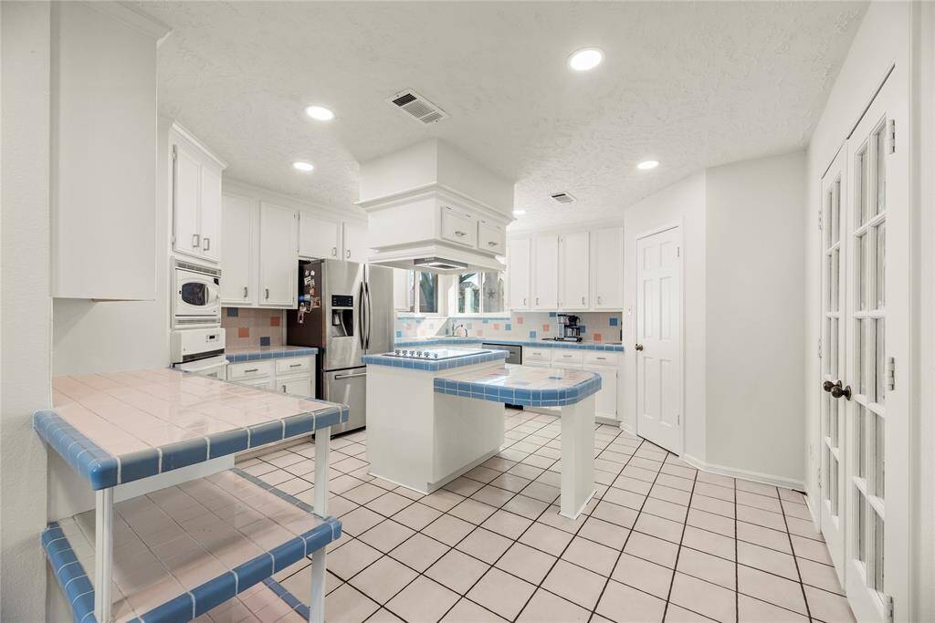 Alternate view of the kitchen featuring a bright, retro design with white cabinetry.