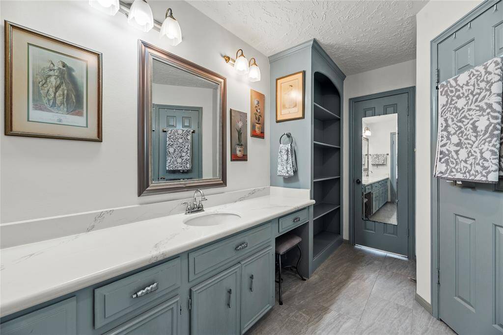 Primary bathroom that features a large vanity countertop with dual sinks, storage drawers, cabinets, and built-in shelving.