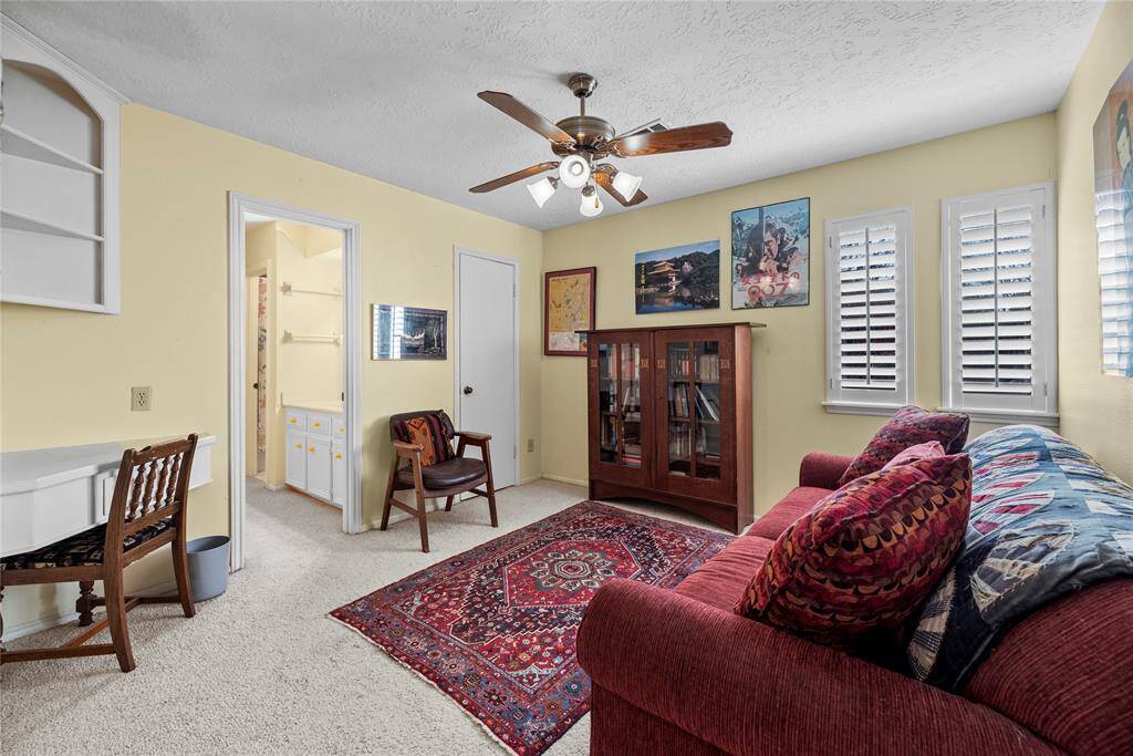 The fourth bedroom is being used like another living room. Featuring carpet flooring, a ceiling fan, and abundant natural light streaming in through multiple windows.