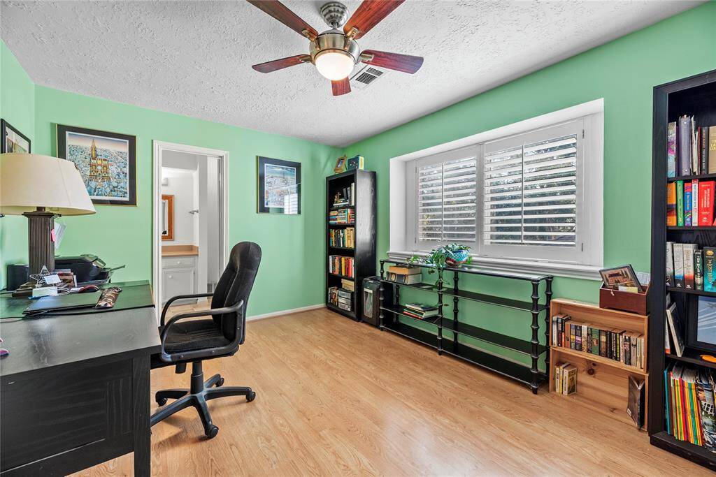 Second floor bedroom being used as a home office, connects to bathroom # 3.  Room features ceiling fan, blind,  and laminate flooring.