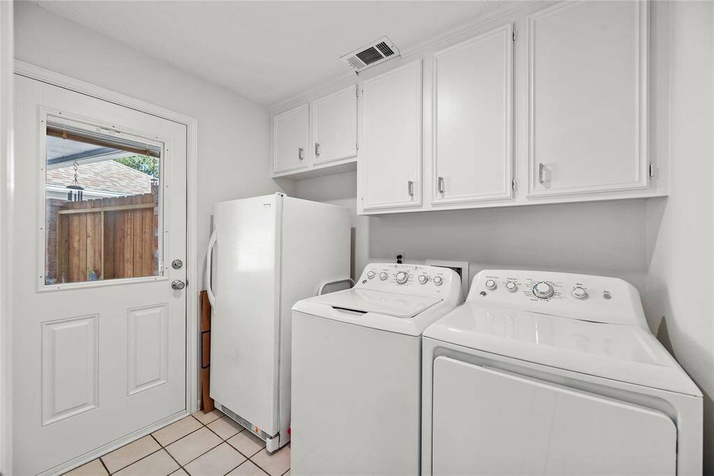 Laundry room large enough for a washer, dryer, and a fridge. There are also built-in cabinets for storage.