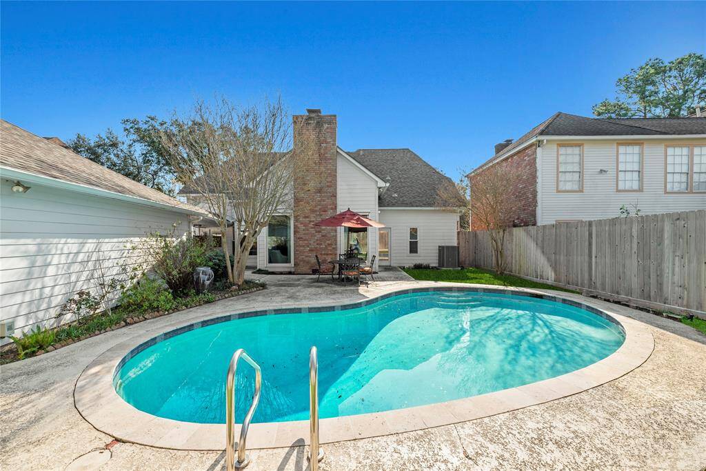 Backyard features a pool, a patio area with outdoor seating and privacy added by a wooden fence in the rear yard.