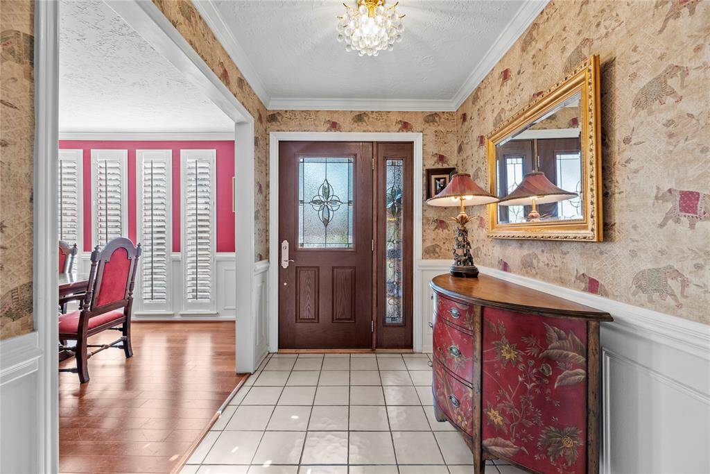This entryway features a wooden door with decorative glass panels, leading into the dining room and the large fmily room.