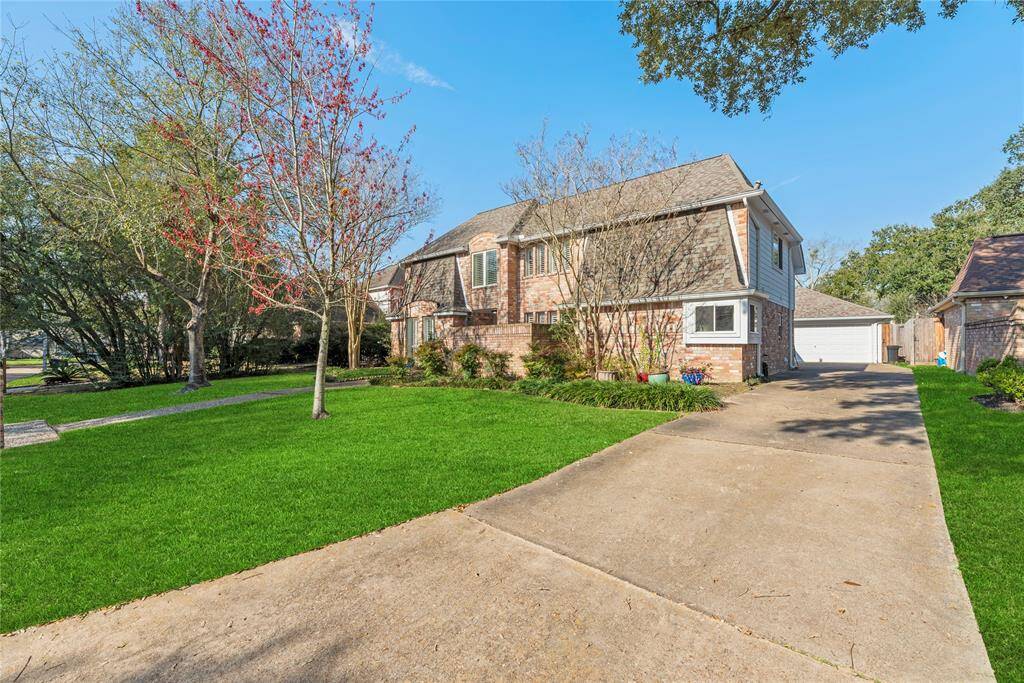 Charming two-story brick home spanning 2,793 sqft, featuring a beautifully maintained front lawn with mature trees.