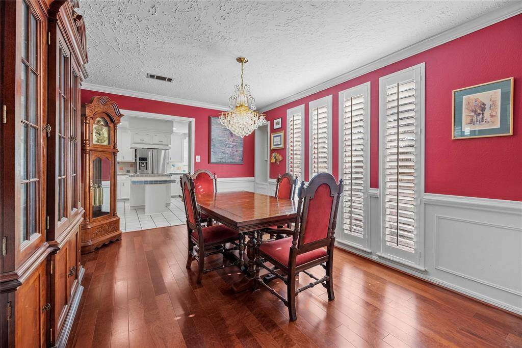 Dining room features hardwood flooring, and a classic chandelier. Large windows with plantation shutters provide ample natural light.