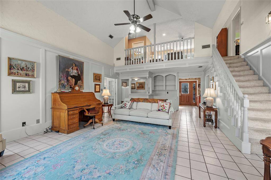 Spacious living room features high ceilings, fireplace, wet bar and open staircase and railing overlook from the upstairs game room.