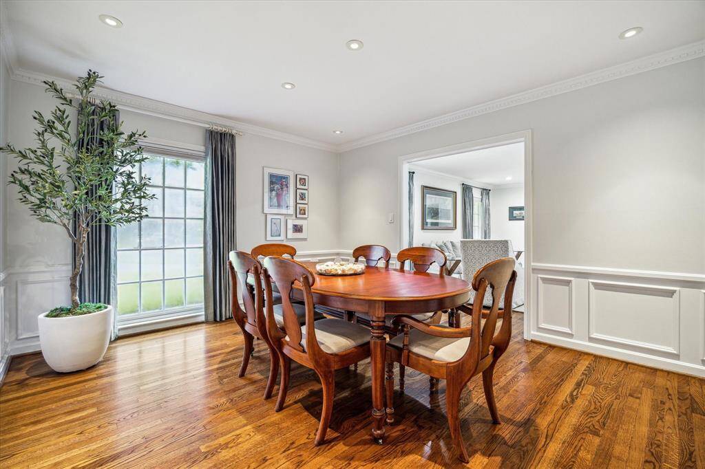Currently styled as a lounge, the formal dining room is adorned with classic wainscotting, dentil molding, and gleaming hardwood floors. A swinging door offers direct access to the kitchen. This space adapts effortlessly to elegant dining or refined relaxation.