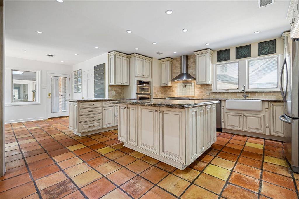 The kitchen offers seamless connectivity to the breakfast room, formal dining, and family room—perfect for both entertaining and daily living. Saltillo tile flooring and west-facing windows fill the space with character and light. Open, airy, and thoughtfully appointed. *Virtually rendered hardwoods*