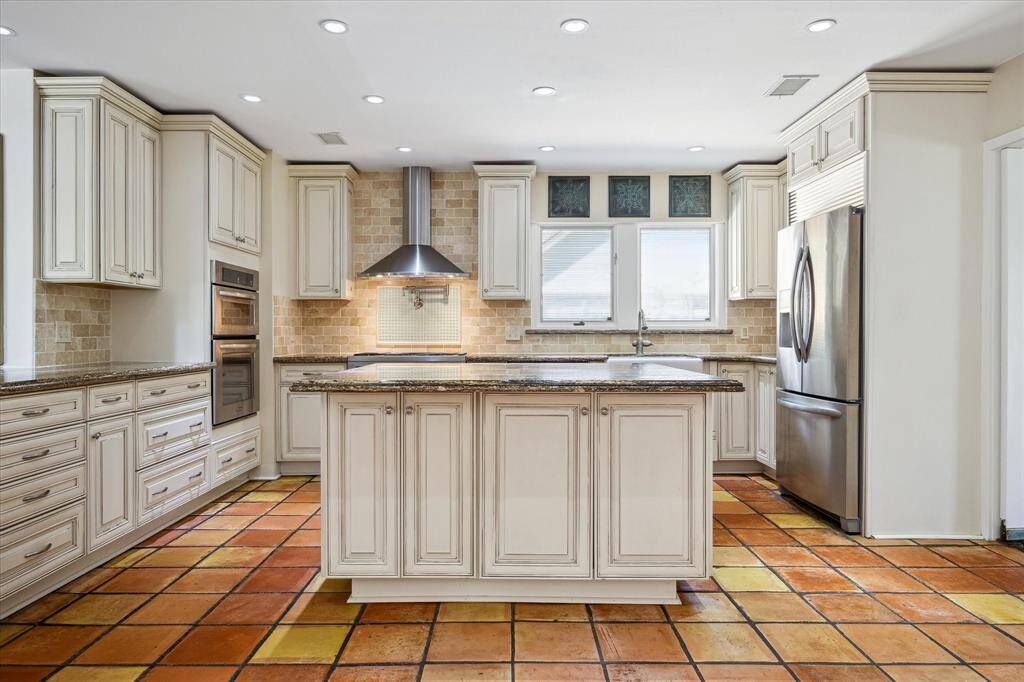 A spacious island with breakfast bar seating anchors the heart of the home. Custom Thomasville cabinetry with smart inserts maximizes storage and function. Recessed LED lighting ensures a bright, inviting atmosphere all day long.