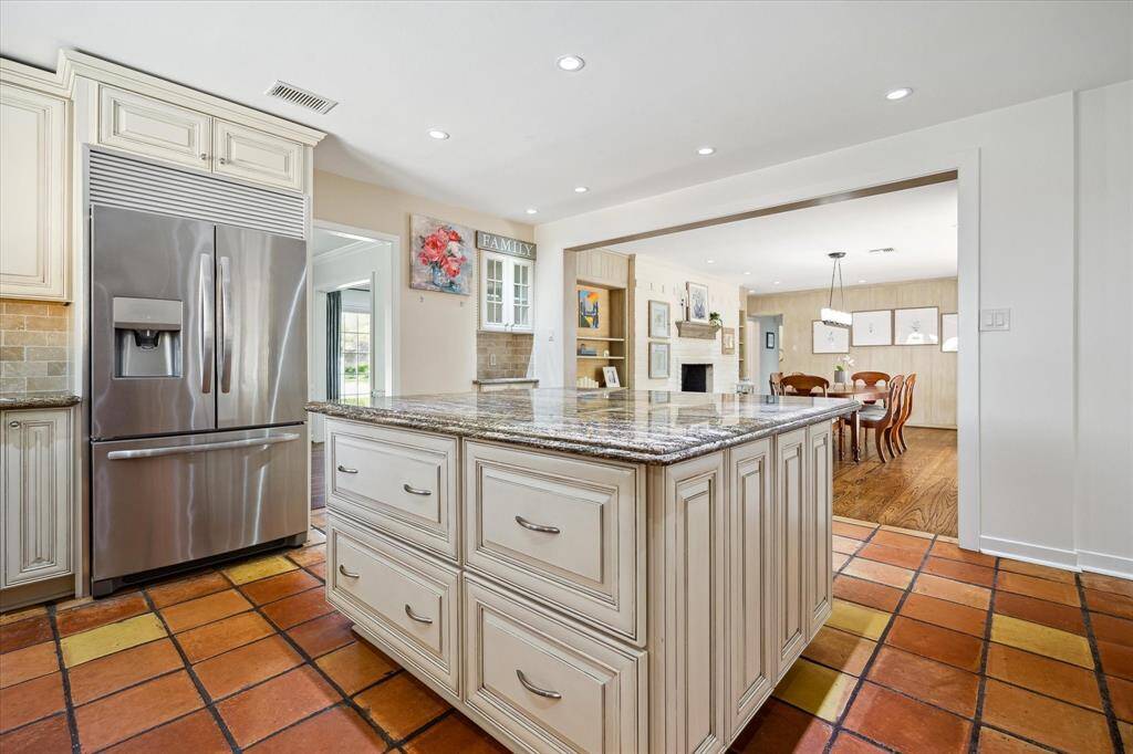 This cheerful breakfast room overlooks the landscaped backyard and patio, offering breezeway access to the guest house. A nearby utility room adds convenience to the charming setting. Dine, relax, and unwind with views of the outdoors.