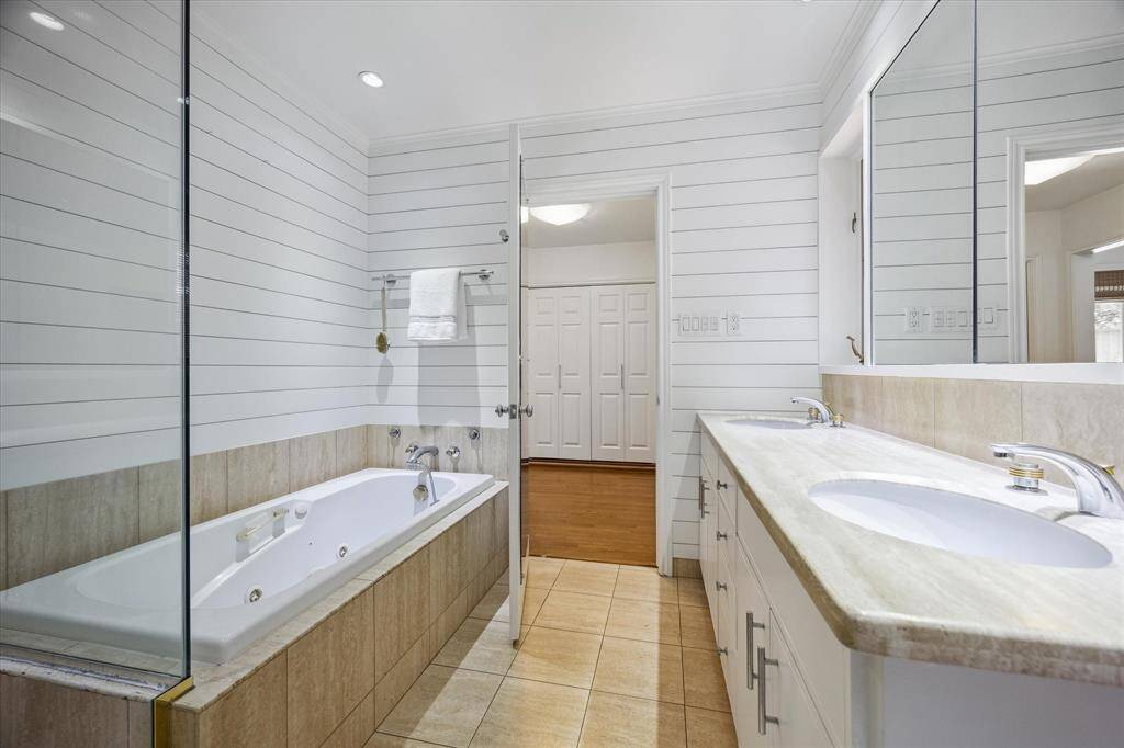 Natural light streams from the bathroom into the connected dressing area, enhancing the spa-like ambiance. Neutral travertine floors and walls exude refined elegance. A peaceful space to begin and end each day.