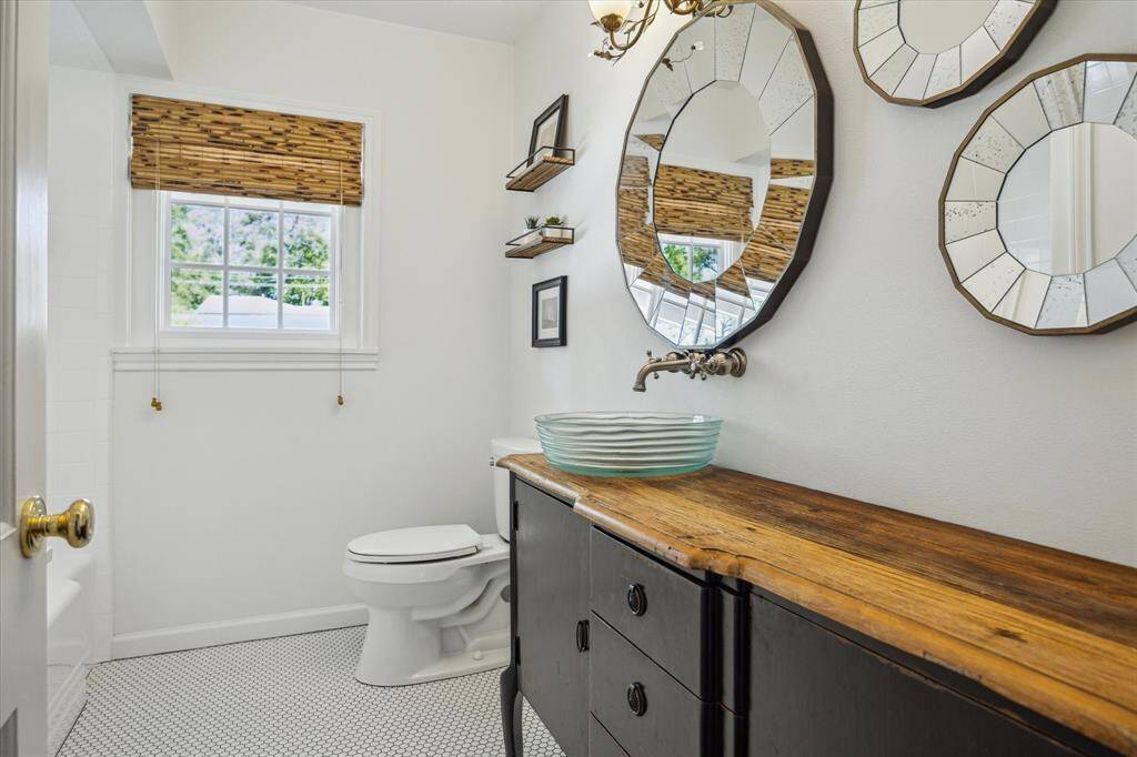 First-floor secondary bedroom includes dual closets with built-in dressers and views of the side yard. Hardwood floors and a ceiling fan offer both style and comfort. A peaceful, light-filled sanctuary.