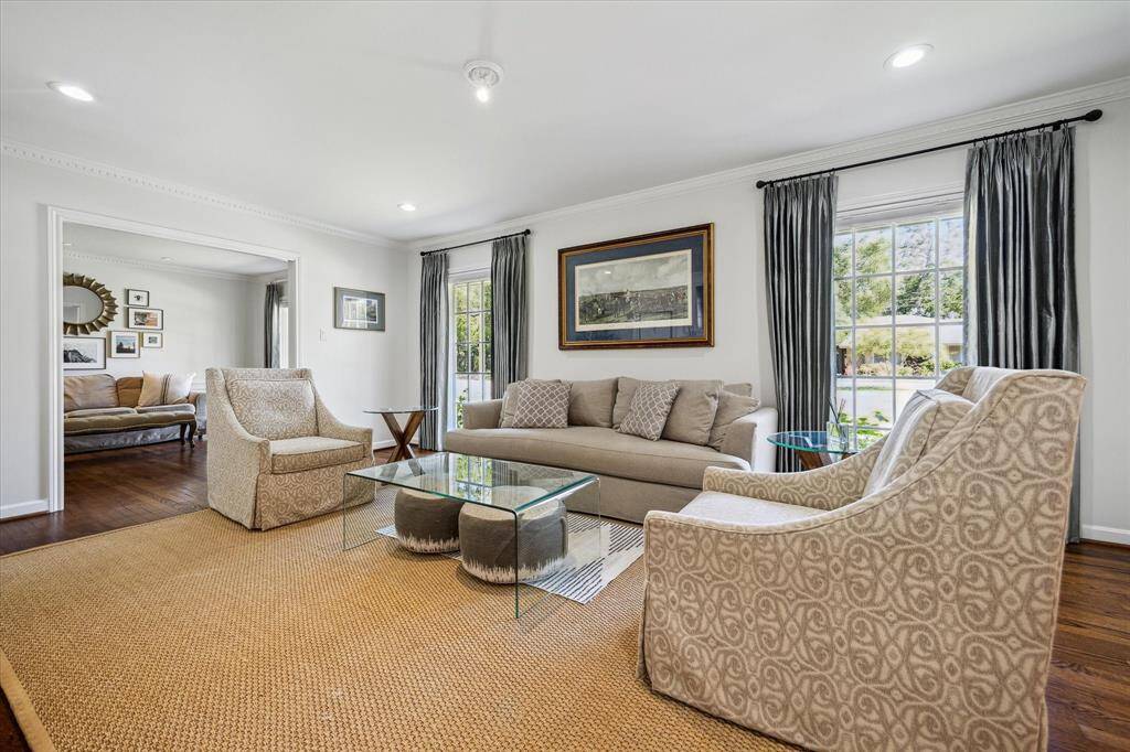 With two large windows overlooking the manicured front lawn, this formal living room is flooded with natural light. Elegant dental crown molding and hardwood flooring elevate the space. Perfectly situated for welcoming guests or quiet afternoons.