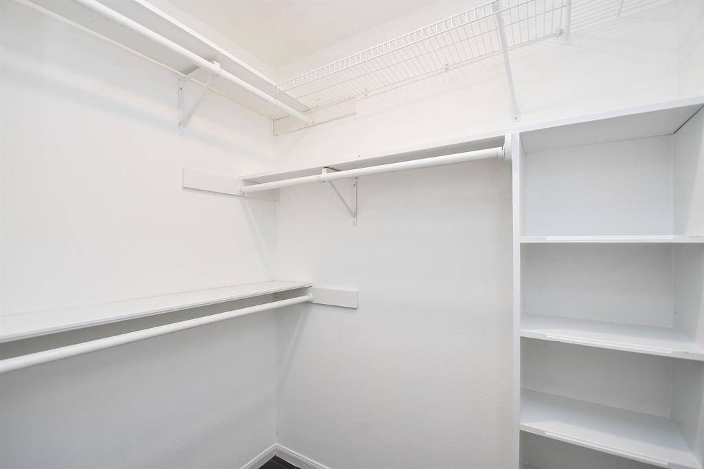 This photo shows a spacious walk-in closet with multiple shelves and hanging rods, offering ample storage space. The clean, white finish adds a bright and organized feel.