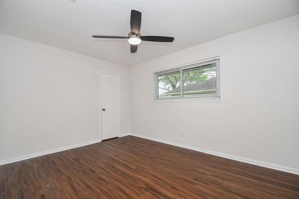 Bedroom #2 features fresh white walls, new flooring, a modern ceiling fan, and a large window that allows natural light to brighten the space.
