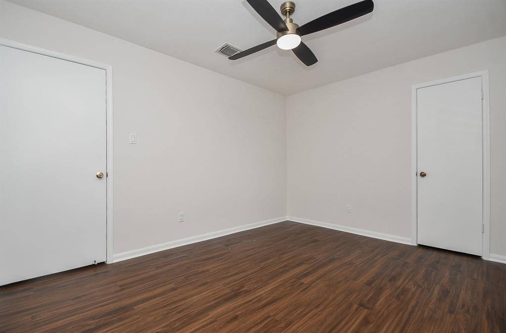 Bedroom #1 features clean white walls, new flooring and a modern ceiling fan