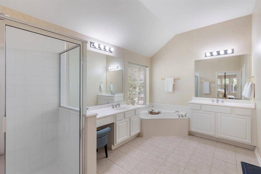 The primary bathroom features dual sinks, a vanity, walk- in shower and a jetted tub.
