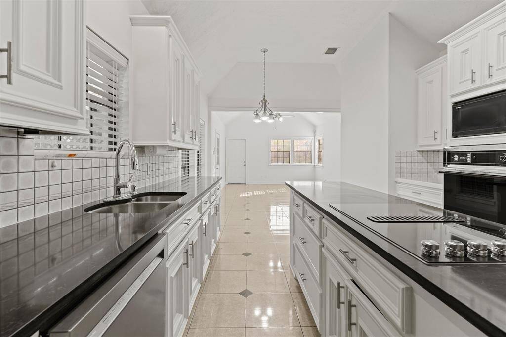 This lovely designed kitchen offers the perfect blend of functionality and style! The sleek black countertops provide a striking contrast against the crisp white cabinetry, creating a modern and timeless aesthetic. A deep sink, high-end appliances, and a spacious island with a built-in cooktop make meal preparation a breeze. The open layout flows seamlessly into the bright breakfast area, where large windows invite in natural light.