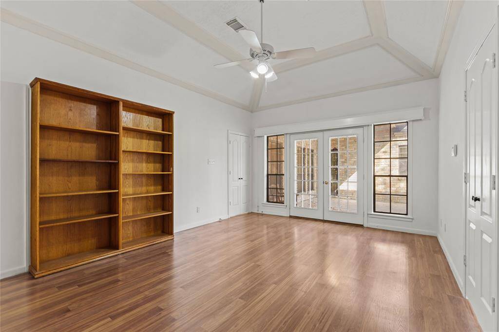 This spacious priary room offers endless possibilities! The soaring tray ceiling adds architectural elegance, while the warm wood flooring brings a cozy touch. Built-in bookshelves provide the perfect space for a personal library, decorative displays, or additional storage. A wall of French doors and windows fills the room with natural light and offers seamless access to the outdoor patio, making it an ideal space for relaxation or creativity.