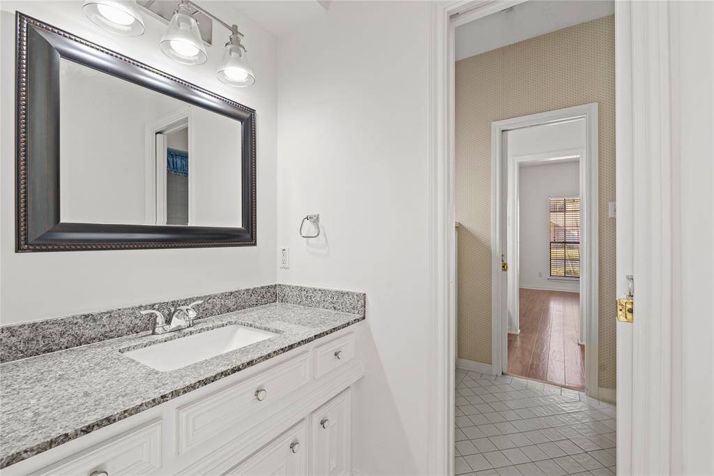 This beautifully designed batf.room offers both style and practicality. The sleek granite countertop, paired with classic white cabinetry, provides ample space for storage while maintaining a clean, modern aesthetic. A stylish framed mirror and elegant lighting create a bright and welcoming atmosphere. Conveniently situated between bedrooms, this bathroom ensures both comfort and accessibility. With its timeless design and functional layout, this space is perfect for family members or guests alike!