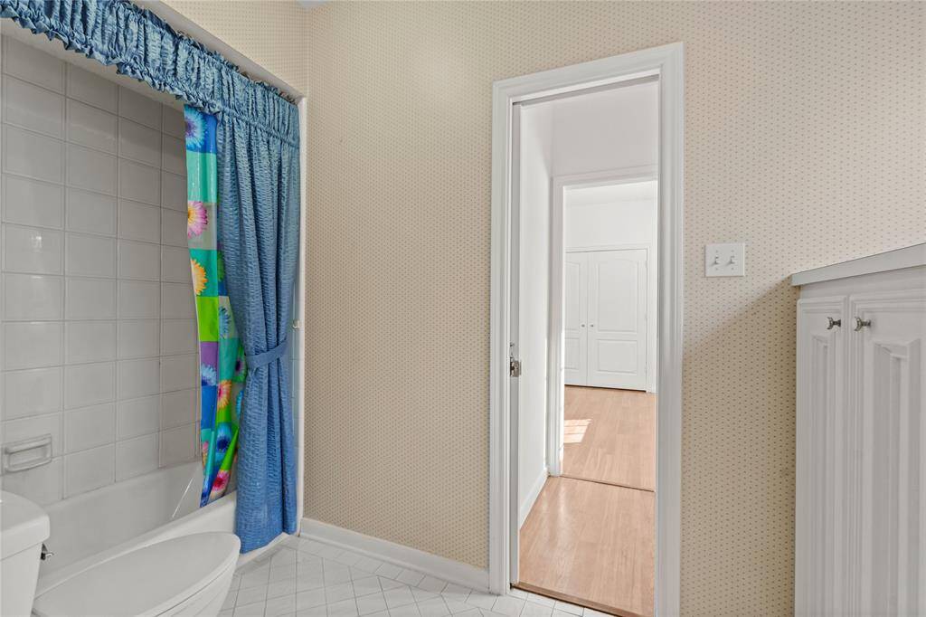 This charming full bathroom offers both functionality and comfort. The classic white tile surrounding the bathtub gives the space a clean and timeless look, while the built-in storage cabinetry provides plenty of room for essentials.The soft neutral wallpaper adds a cozy touch, making this space feel warm and inviting.Conveniently located near the bedrooms, this bathroom is perfect for family use or accommodating guests.