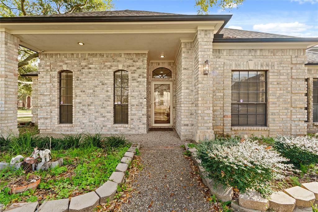 This charming front entrance welcomes you with timeless brick architecture and a beautifully framed glass door, setting the tone for the warmth and elegance found within. The covered porch provides a cozy touch, perfect for greeting guests or enjoying a peaceful moment outdoors. Arched windows add character while allowing natural light to flow inside. The landscaped garden beds, lined with lush greenery, enhance the home's curb appeal, creating a picturesque and inviting first impression