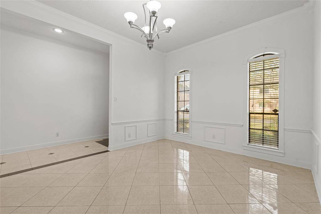 This beautifully designed dining space is perfect for creating memorable meals and gatherings! The elegant chandelier adds a touch of sophistication, while the classic wainscoting and crown molding elevate the room's timeless charm. Tall arched windows let in natural light, creating a warm and inviting atmosphere. The open flow into the adjoining spaces makes this area both functional and welcoming-ideal for hosting dinner parties or enjoying quiet family meals.