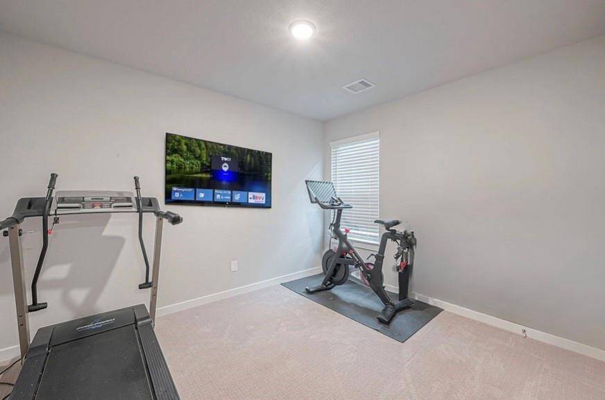 View of secondary bedroom currently being used as an exercise room. (TV virtually staged)