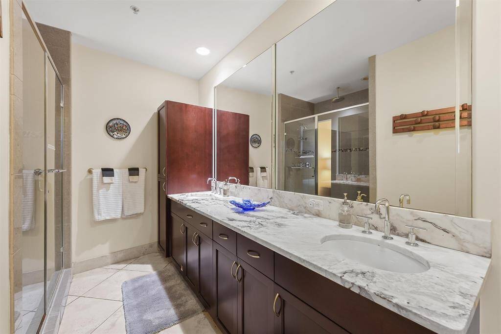 Elegant en-suite bathroom with double vanities, a walk-in glass shower, and luxurious finishes throughout.