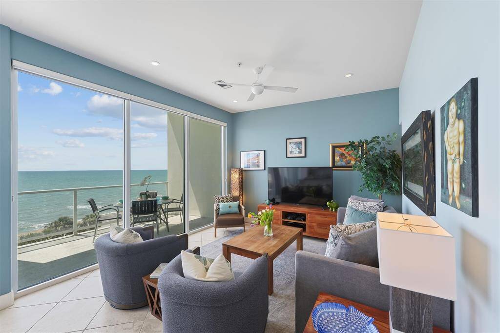 Stylish open-concept living area with upscale furnishings, floor-to-ceiling windows, and direct access to the expansive balcony overlooking the Gulf