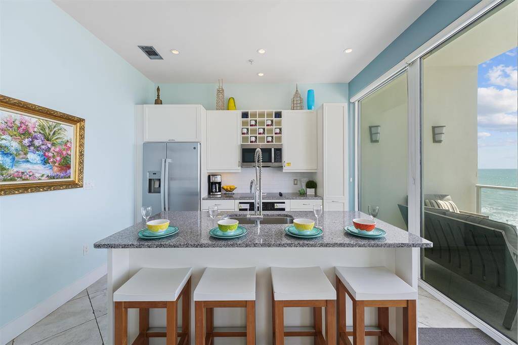 Modern kitchen featuring stainless steel appliances, sleek cabinetry, granite countertops.
